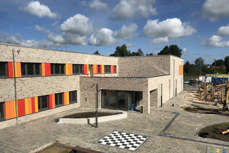 Grundschule Brake-Harrien -Neubau einer zweigeschossigen Grundschule mit Sporthalle in Brake -Außenansicht Schulgebäude und Pausenhof mit Spielgeräten